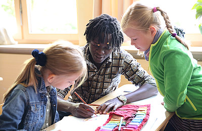 Freiwilliger hilft zwei Schülerinnen beim FSJ Schule