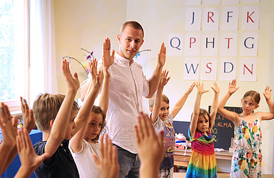 Freiwilliger steht mit den Kindern im Morgenkreis im FSJ in der Schule