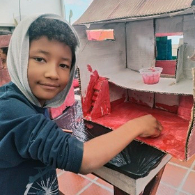 Emergency pedagogy in Colombia A child makes a house out of cardboard as part of emergenc pedagogy in Colombia